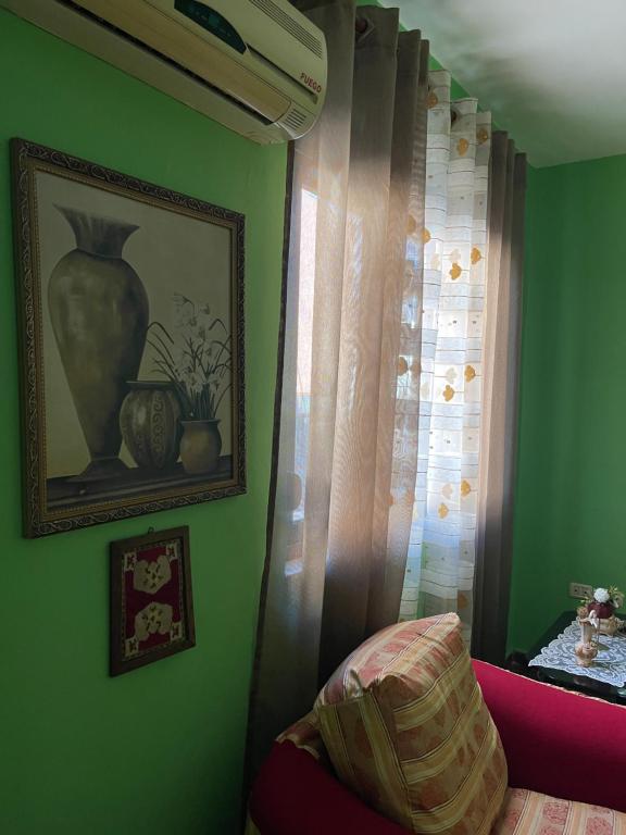 Una habitación verde con un jarrón y una ventana. en City Center, en Durrës