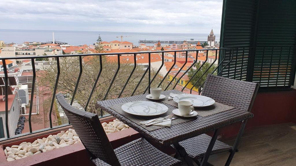 a table with two cups and plates on a balcony at Funchal Apartament Marina View with PARKING FREE in Funchal