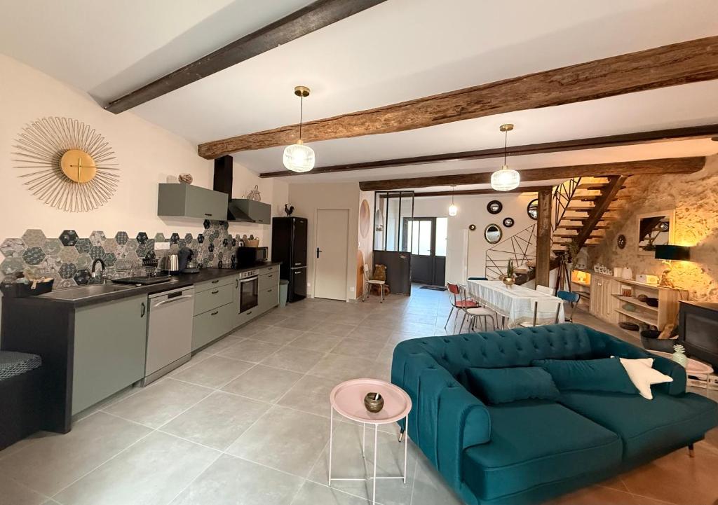ein Wohnzimmer mit einer blauen Couch und einer Küche in der Unterkunft Maison de bourg au coeur du village médiéval in Saint-Macaire