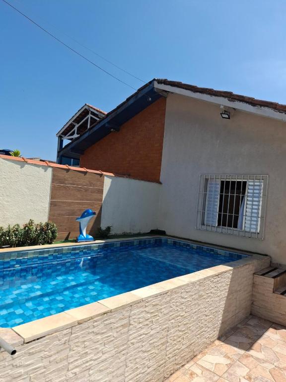 a swimming pool in front of a house at Casa com churrasqueira e piscina in Itanhaém