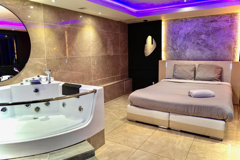 a bedroom with a tub and a bed with purple lighting at Suite Spa privative avec jacuzzi, massage & sauna in Fontenay-aux-Roses