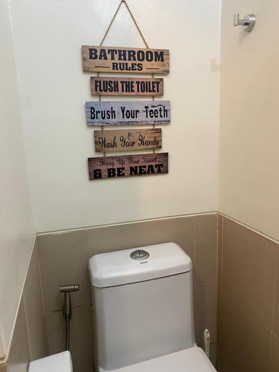 a bathroom with a toilet and a sign on the wall at Davao Staycation near abreeza and sm lanang in Davao City