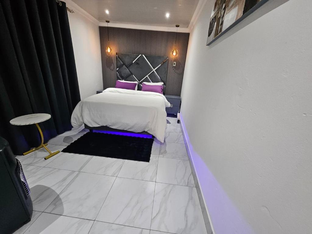 a bedroom with a white bed with purple pillows at luxurious one bedroom apartment in Kempton Park
