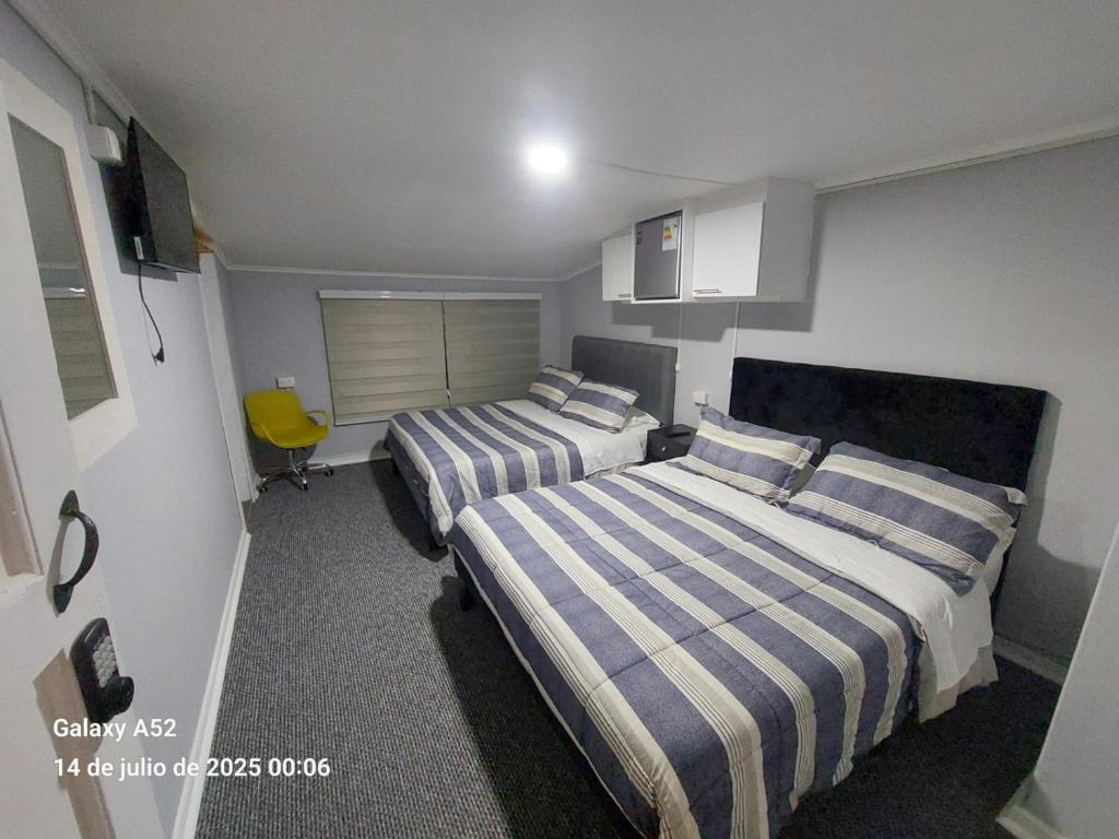 a hotel room with two beds and a yellow chair at Hostal Don Francisco in Osorno