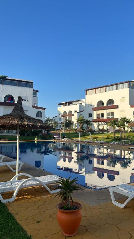 a resort with a pool with chairs and an umbrella at Cabo House in Cabo Negro