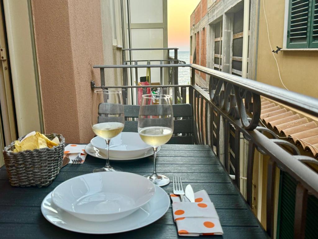 a table with two glasses of wine on a balcony at Casa Antonella - Taormina mare in Mazzeo