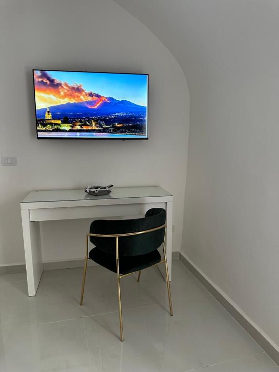 Un escritorio con una silla y un televisor en una pared. en Al Fiko Suite, en Catania
