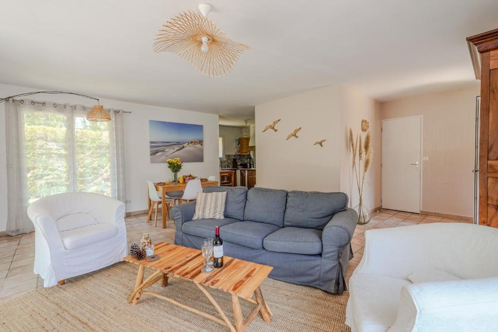a living room with a blue couch and a table at L'Eyre de vacances -Proche Lac Arjuzanx - jeux - terrasse - plancha - in Luglon