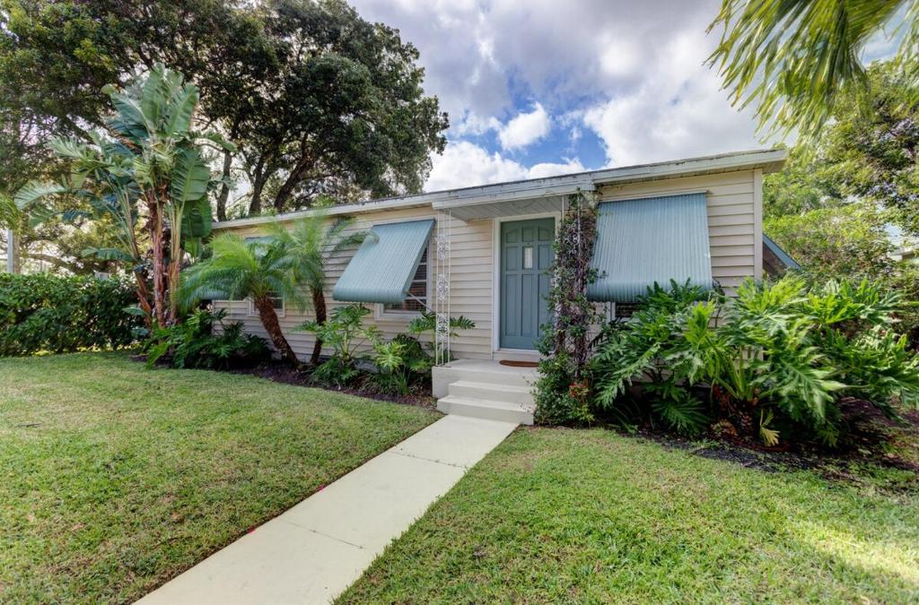 a small white house with blue shutters on it at Charming West Palm Beach Home in West Palm Beach