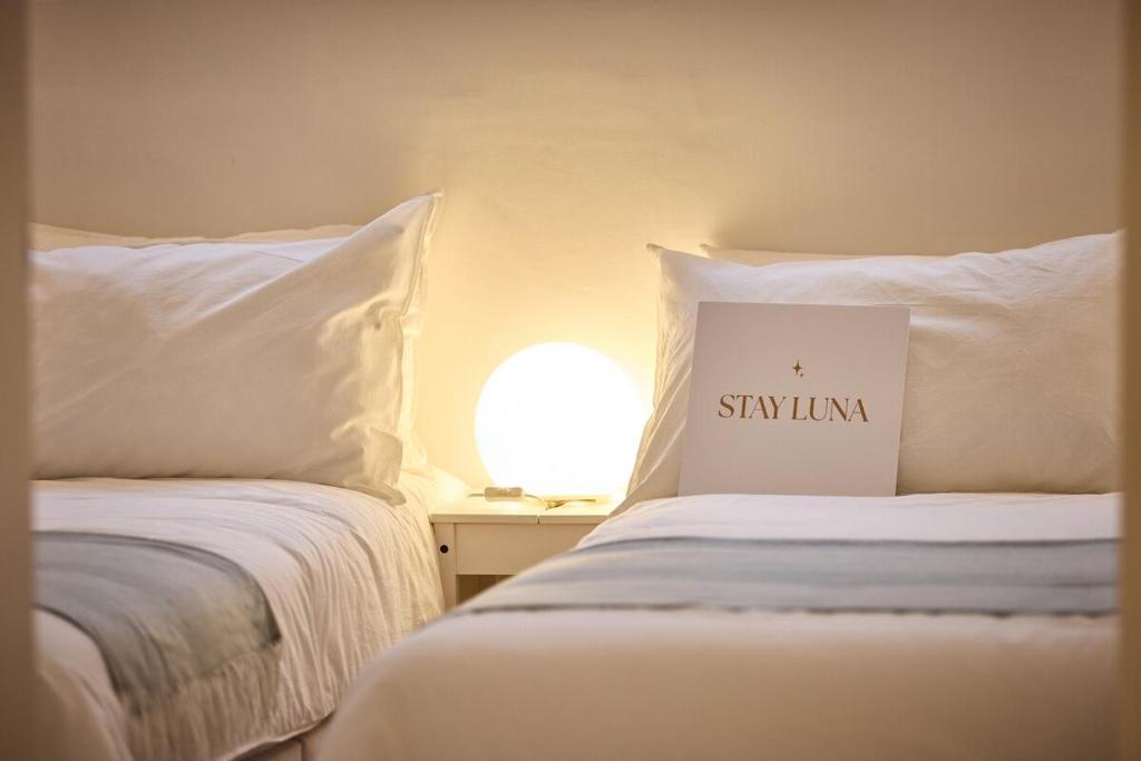 Un dormitorio con dos camas con almohadas blancas y un cartel. en Stay Luna, en Seúl