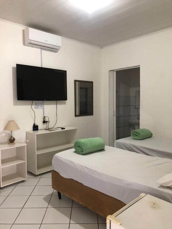 a bedroom with two beds and a flat screen tv at Pousada Irmão Sol Irmã Lua in Abadiânia
