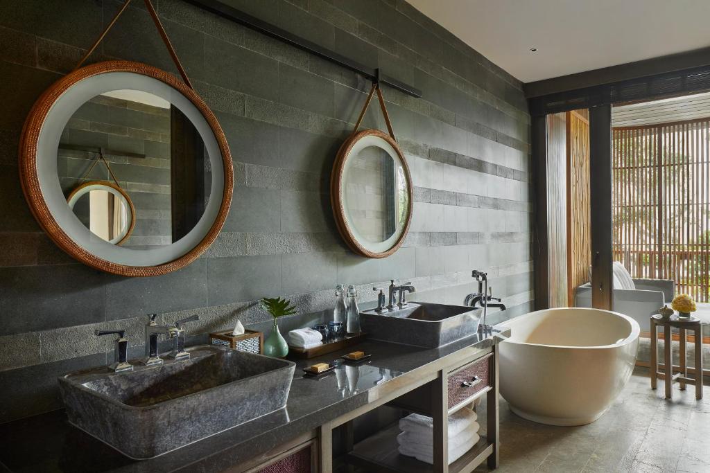 a bathroom with two sinks and a tub and mirrors at Andaz Bali, By Hyatt in Sanur