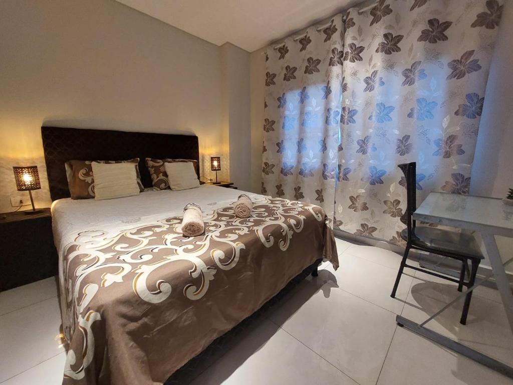 Un dormitorio con una cama con un escritorio y una ventana. en Modern apartment with pool, near Costanera beach, en Encarnación
