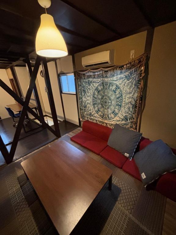 a living room with a red couch and a tapestry at ワカバハウス in Wada