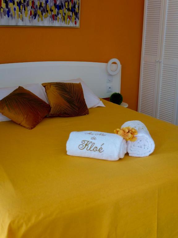 un letto giallo con due asciugamani sopra di Au Nid de KLOE, plage & piscine a Grand-Bourg