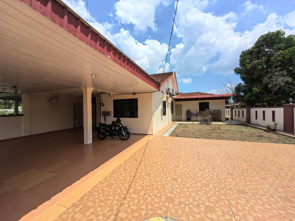 a building with a motorcycle parked outside of it at Lagenda Serai Wangi Homestay in Padang Serai
