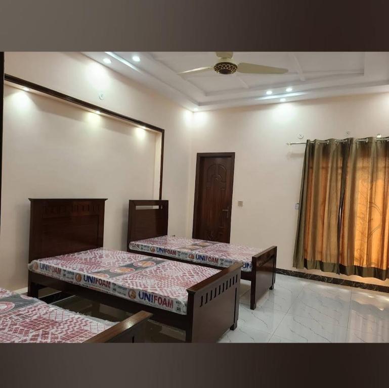 a room with two beds in a room with a window at Al-Jannat Girls Hostel in Lahore