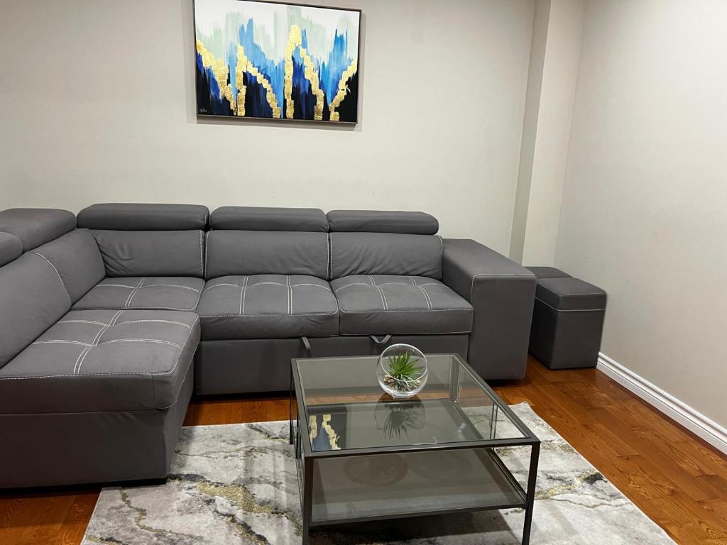 a living room with a gray couch and a glass table at Three Bedrooms House in Mississauga with free parking Conveniently located with easy access to the airport downtown Toronto major malls and highways for a seamless stay in Mississauga