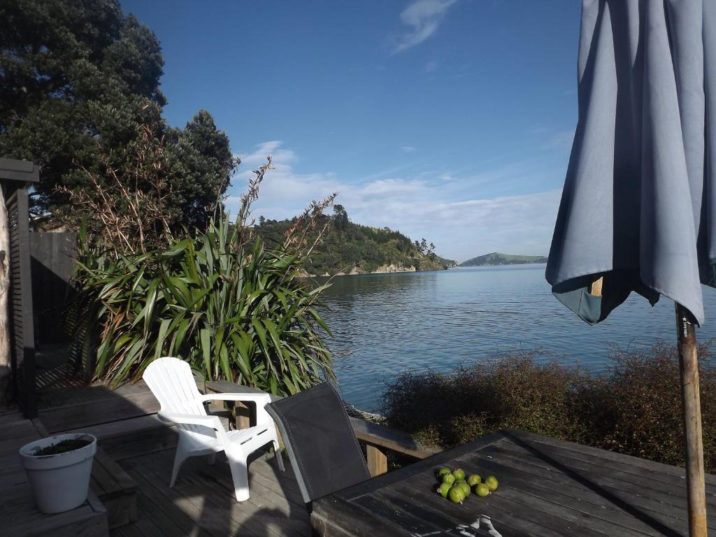 an umbrella and chairs and a table with a view of a lake at Long Bay Motor Camp in Coromandel Town