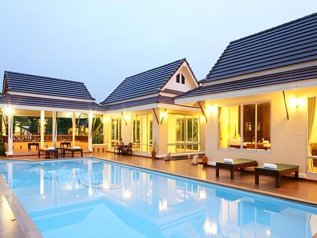 a house with a swimming pool in front of it at The Forest Home Resort in Nakhon Nayok