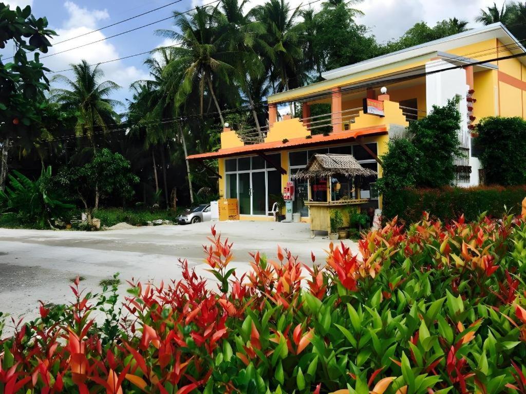 a yellow house with red flowers in front of it at The Royhanna Beach House in Tab Kaek Beach