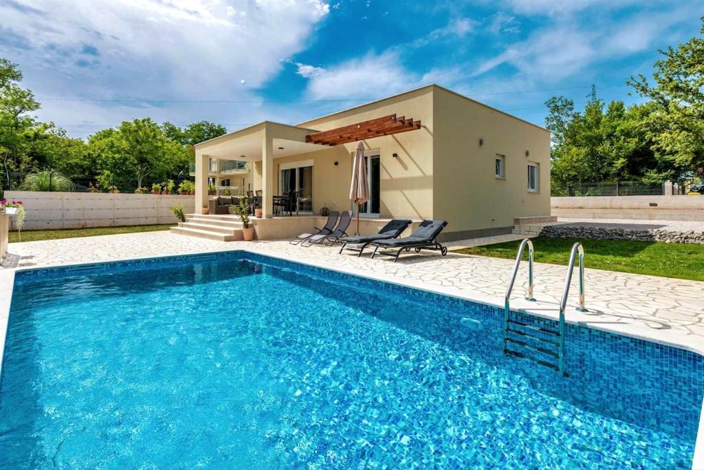 a swimming pool in front of a house at Villa Grace, a romantic single story villa with a pool in VeliGolji