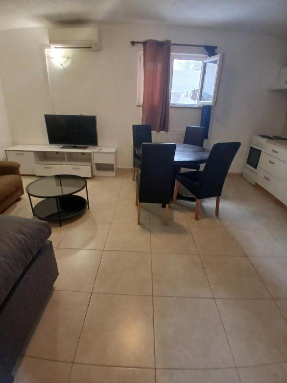a living room with a table and chairs and a television at Ž apartmani in Zadar