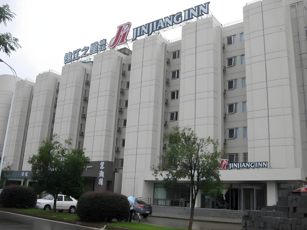 un grand bâtiment blanc avec une enseigne dessus dans l'établissement Jinjiang Inn Wuhan Huanghelou Fuxing Road Metro Station, à Wuhan