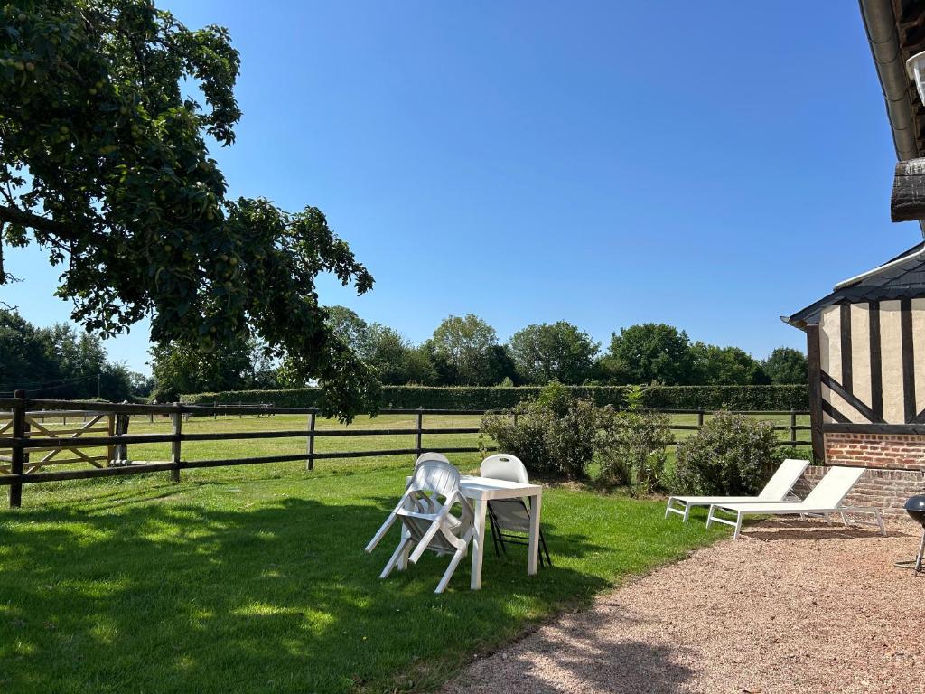 two white chairs and a table in the grass at La Longere du Haras in Manerbe