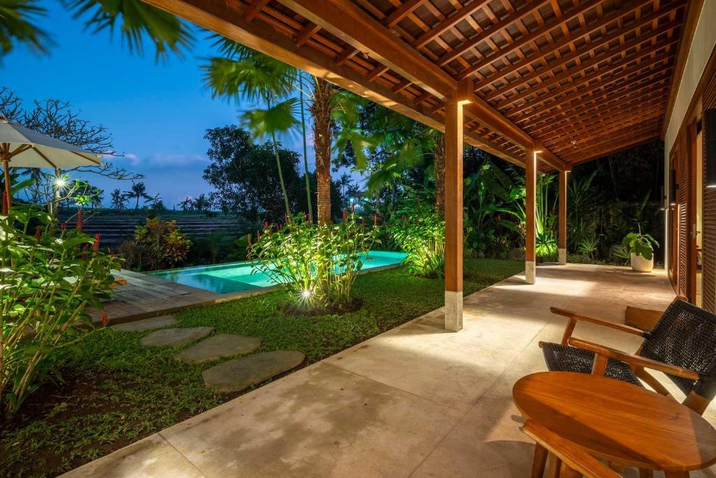 un patio con piscina, mesa y sillas en 3 BR Barani Villa Tanah Lot with Rice Paddy View & Private Pool, en Tanah Lot
