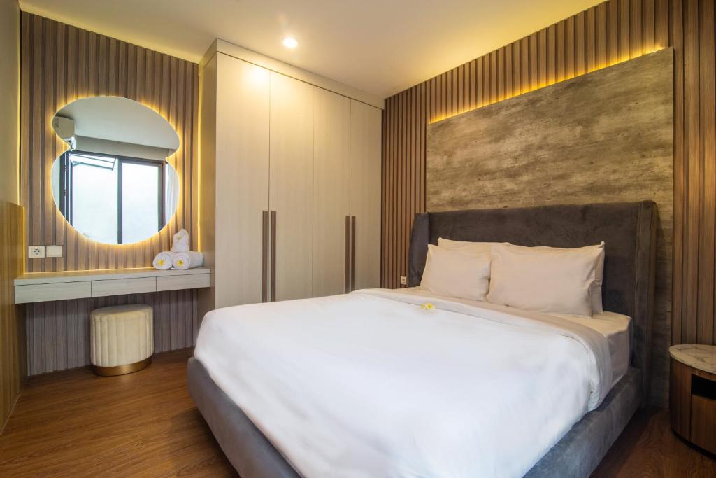 Un dormitorio con una gran cama blanca y un espejo. en Casa de la Vida, en Tanah Lot
