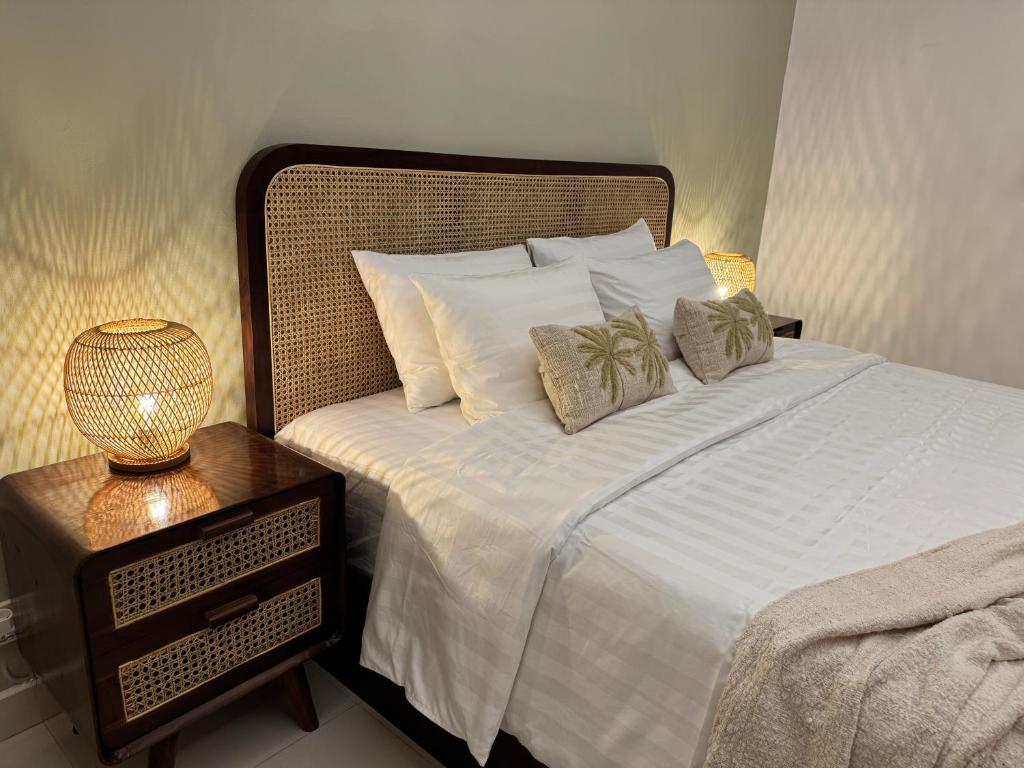 a bed with white sheets and pillows next to a night stand at Villa Kuu - Elegant 2BR Villa with Private Pool in Kerobokan