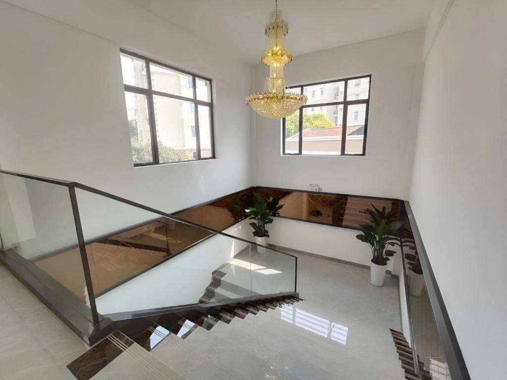 a glass staircase in a white room with a chandelier at Shell Shanghai Baoshan District Songbin Road Subway Station Hotel in Hujiazhai
