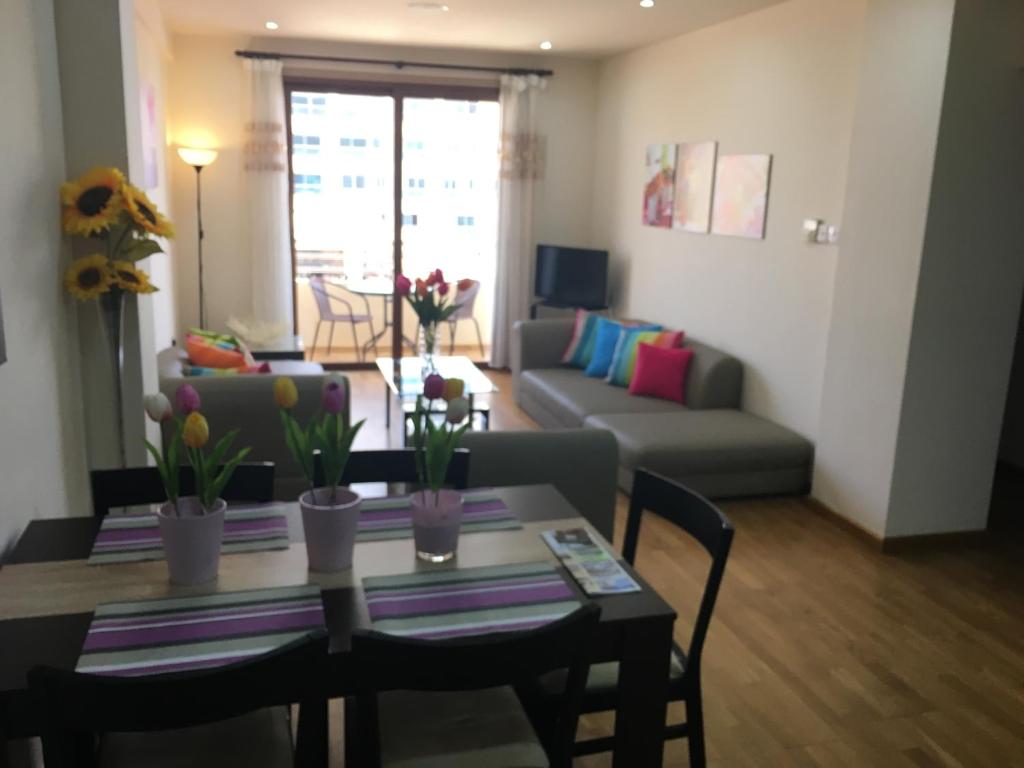 ein Wohnzimmer mit einem Tisch und einem Sofa in der Unterkunft Ithaki Phinikoudes Apartment No. 205 in Larnaka