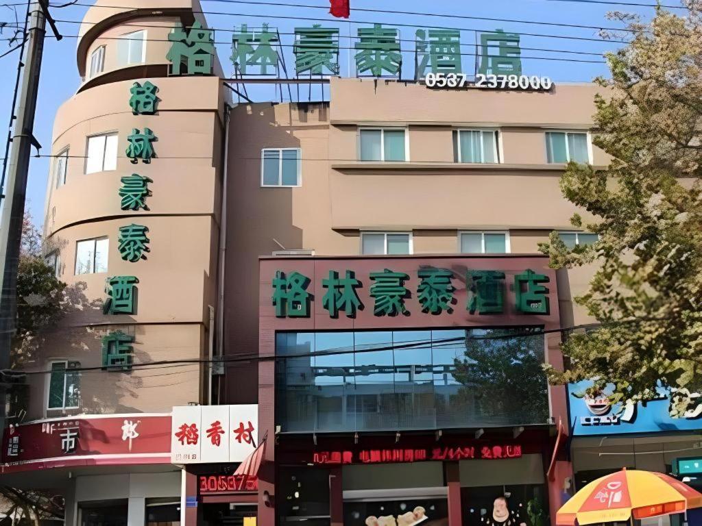 a building with signs on the side of it at GreenTree Inn Jining Jianshe Road Hotel in Jining