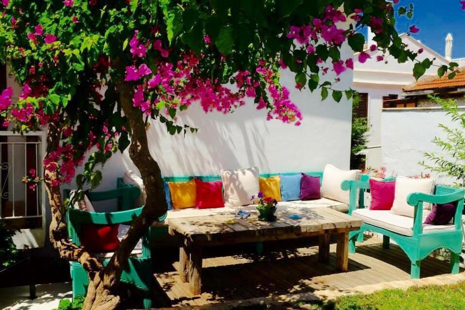 un patio con sofá y un árbol con flores rosas en The White House Kalkan, en Kalkan