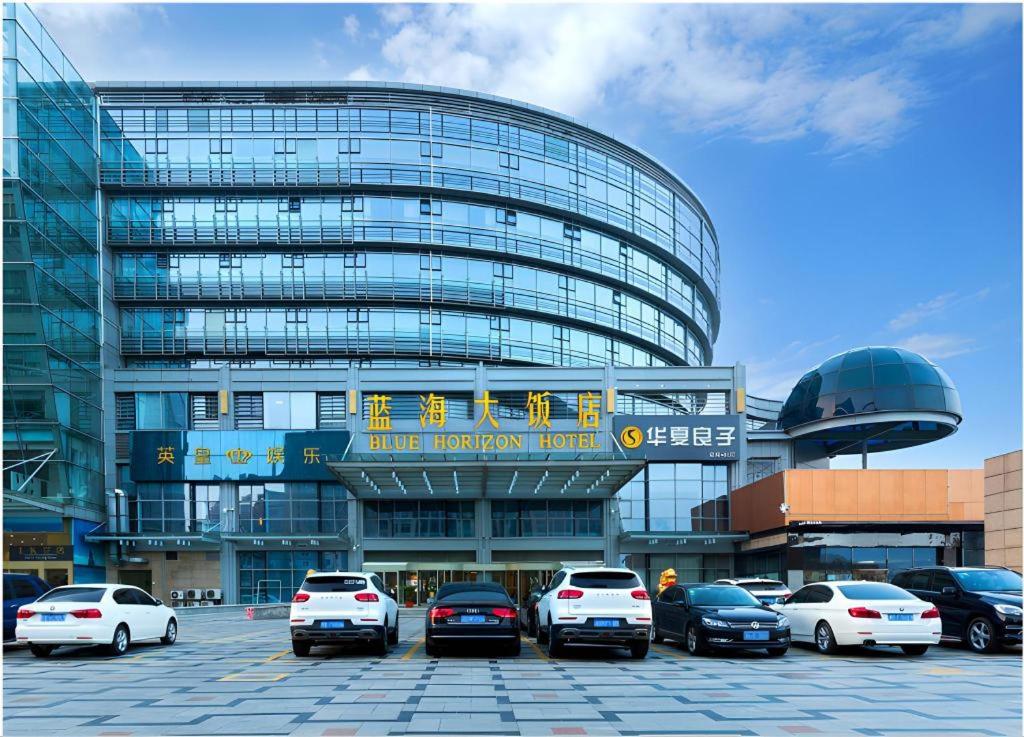 a building with cars parked in a parking lot at Qingdao Blue Horizon Hotel Laoshan in Qingdao