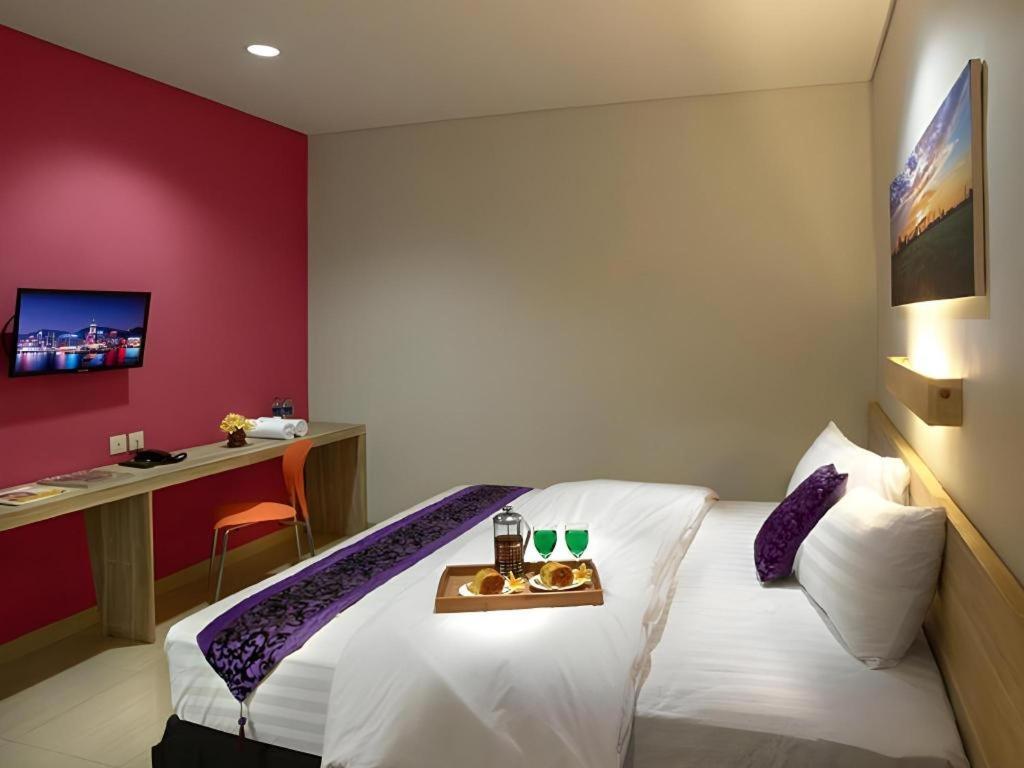 ein Schlafzimmer mit einem Bett, auf dem ein Tablett mit Essen steht in der Unterkunft Life Puri Hotel Surabaya in Surabaya