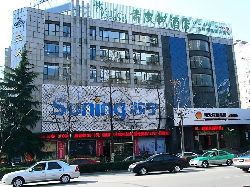a large building with cars parked in front of it at Vatica HeFei Baishuiba BHG Hotel in Hefei