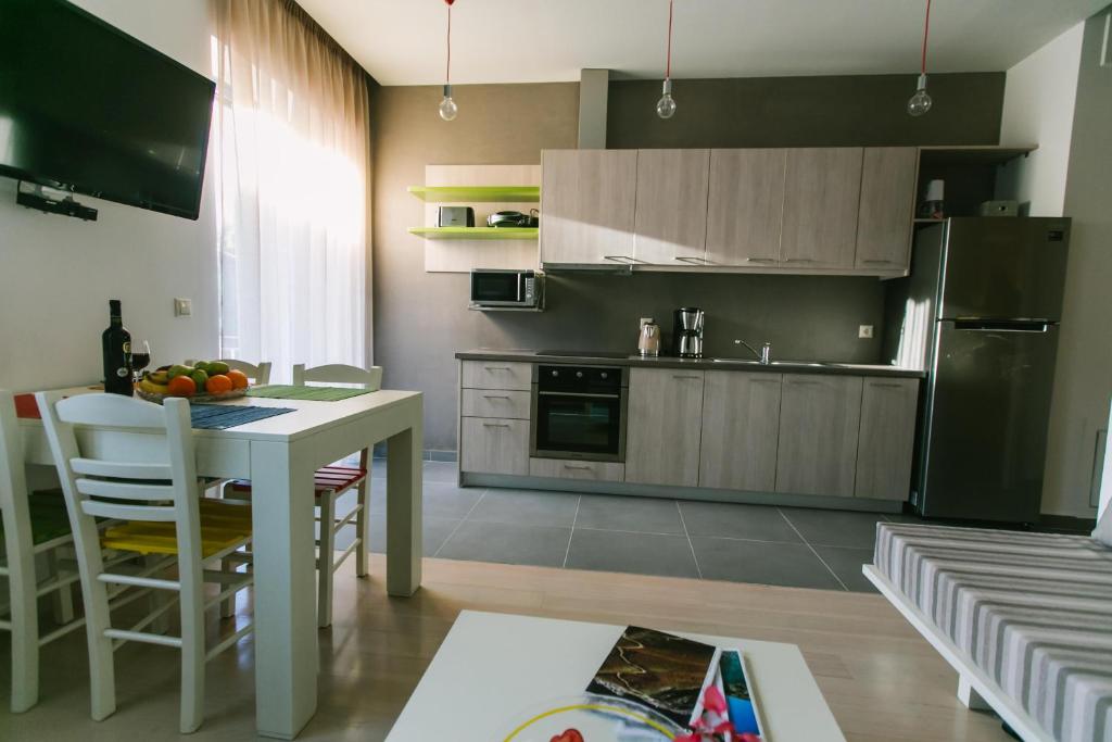 una cucina con tavolo, frigorifero e armadi di Maistros Kardamyli Apartments a Kardhamili