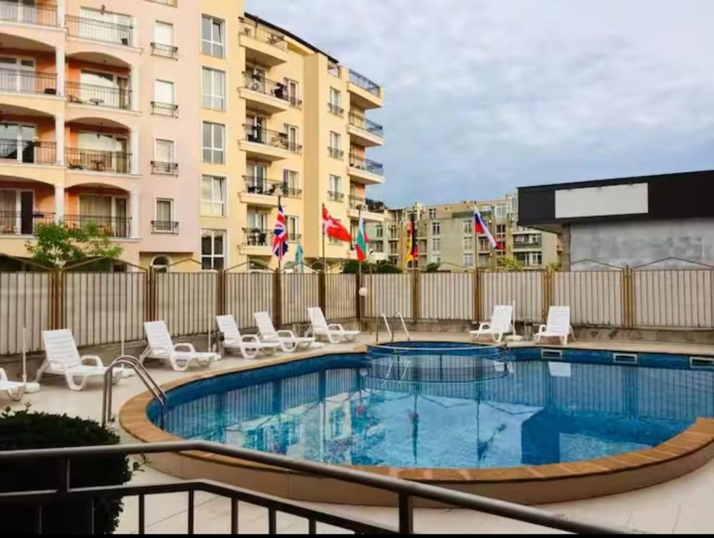 a swimming pool with chairs and a building at One Sunny Home in Sunny Beach in Sunny Beach