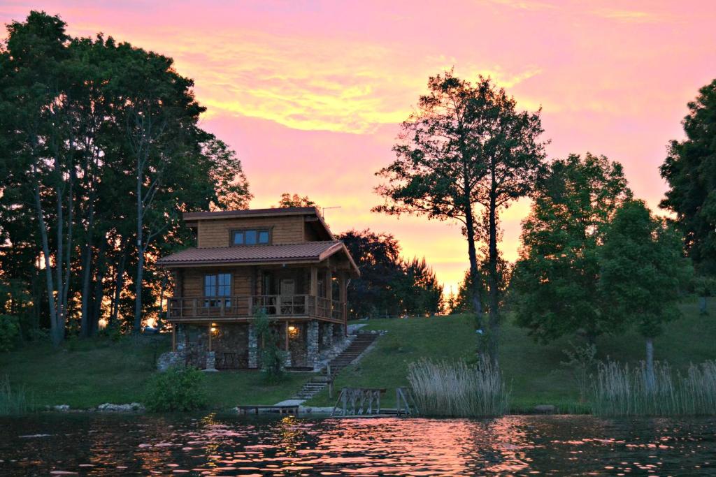 una casa sentada en la cima de una colina junto a un lago en Mekų sodyba, en Degučiai