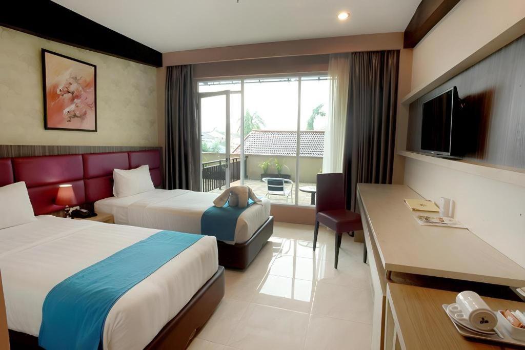 a hotel room with two beds and a television at Asoka Luxury Hotel in Bandar Lampung