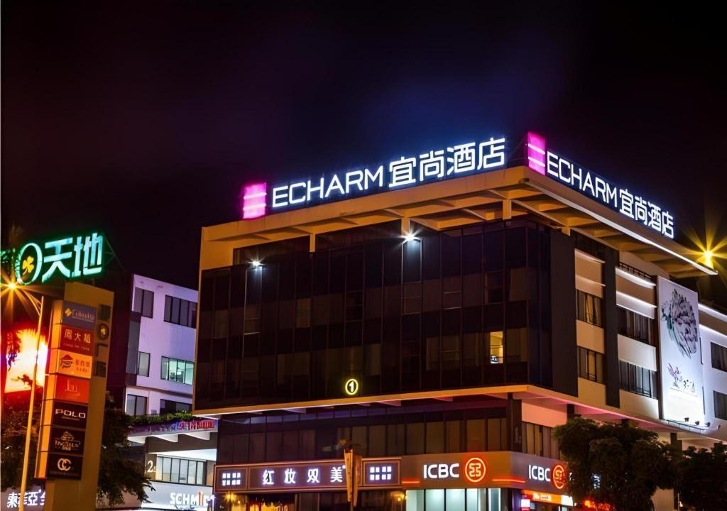 a building with neon signs on top of it at Echarm Hotel Danzhou Xiari Plaza in Danzhou