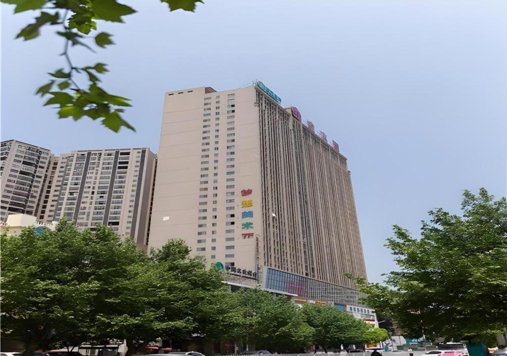 un grand bâtiment avec des arbres devant lui dans l'établissement City Comfort Inn Yongzhou Jinshuiwan, à Guzhuting