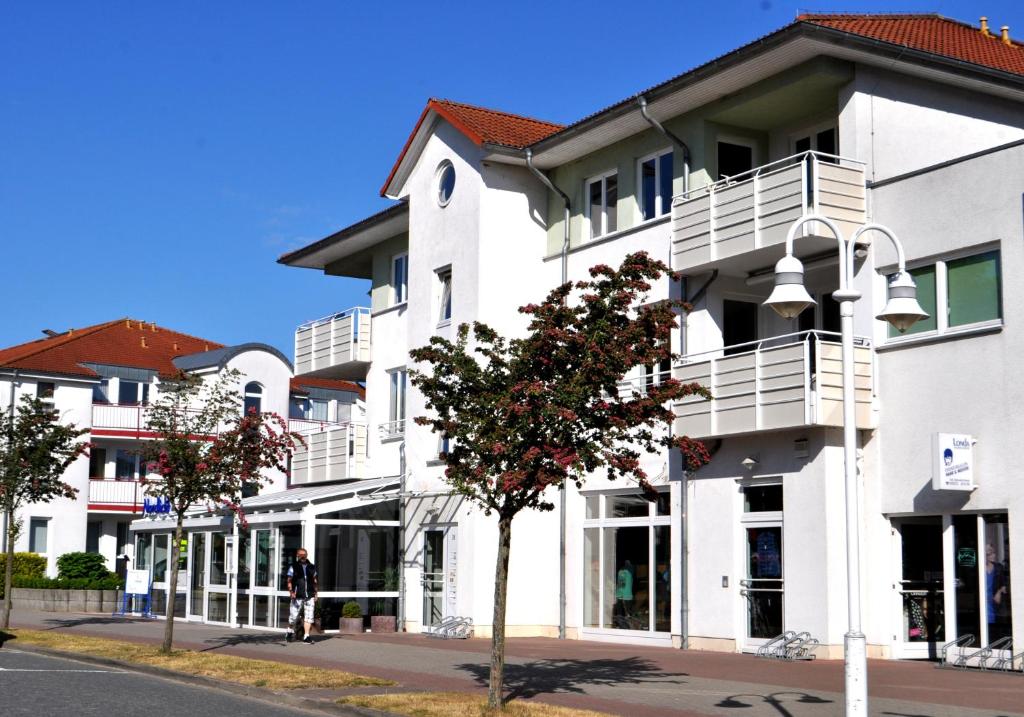 ein weißes Gebäude mit weißen Balkonen auf einer Straße in der Unterkunft Ferienapartment Wellenreiter Insel Usedom in Ostseebad Karlshagen