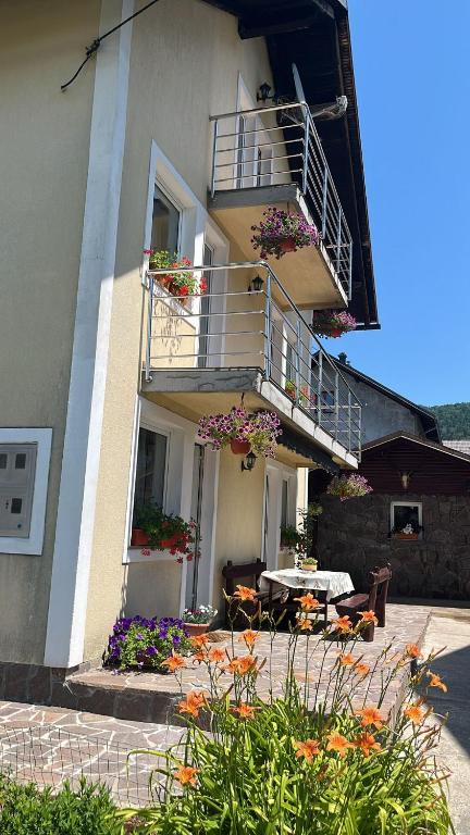 a building with a balcony and a table and flowers at Drago Kremenjaš in Delnice