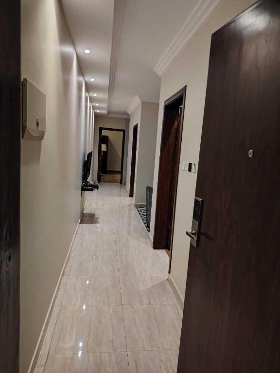 a hallway with a long corridor with doors and a tile floor at خزامى للشقق المخدومة in Sufan