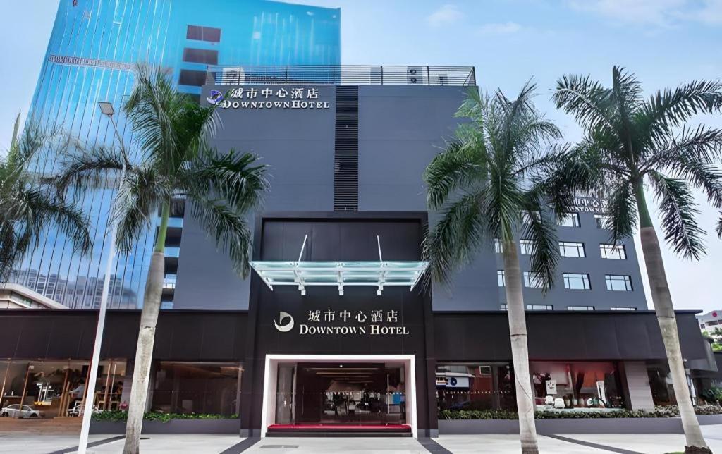 a building with palm trees in front of it at Downtown Hotel in Zhuhai