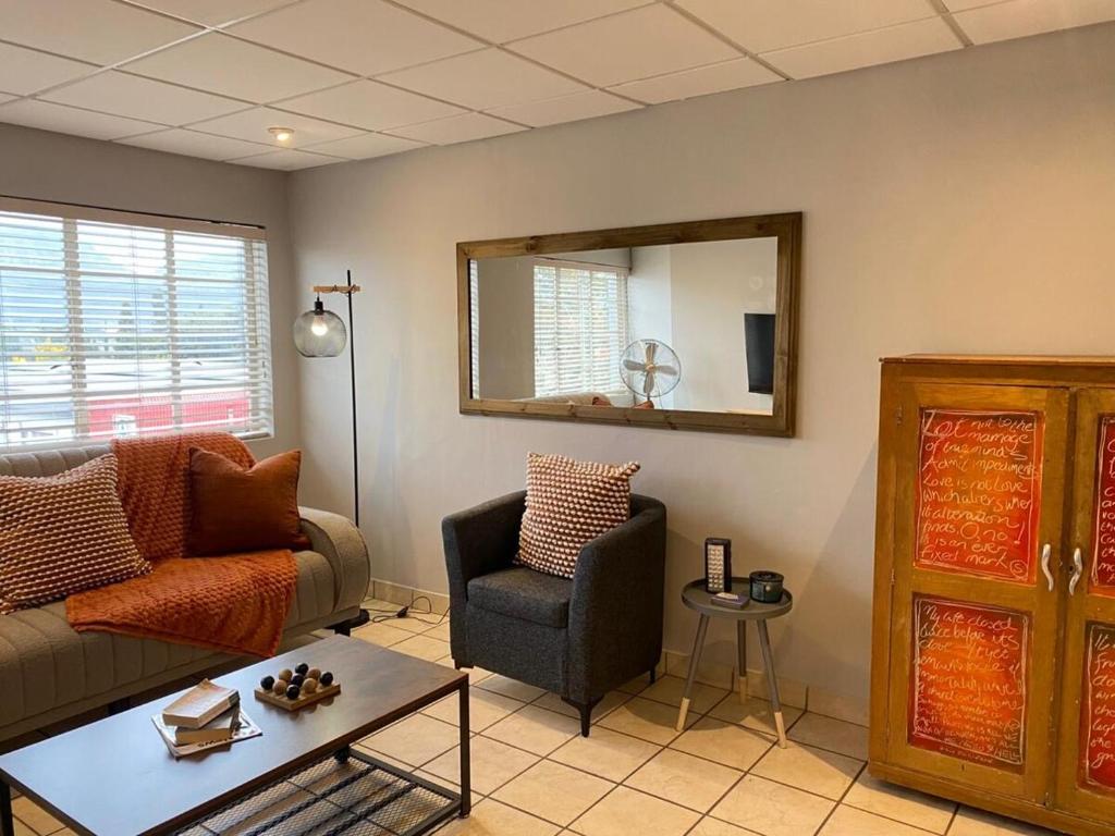 een woonkamer met een bank, een stoel en een spiegel bij Nunu's Self Catering Apartment in Paarl